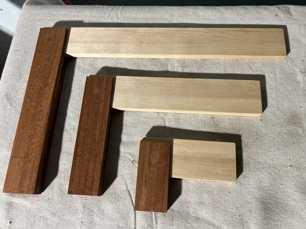 Three try squares sitting on a workbench.